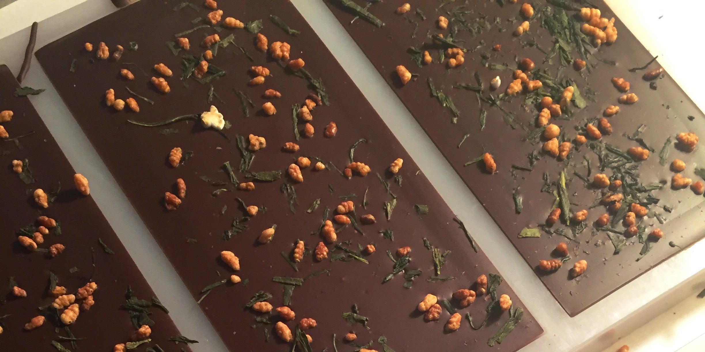 A back side of a dark chocolate bar by Saratoga Chocolate Co with green tea and brown rice on it