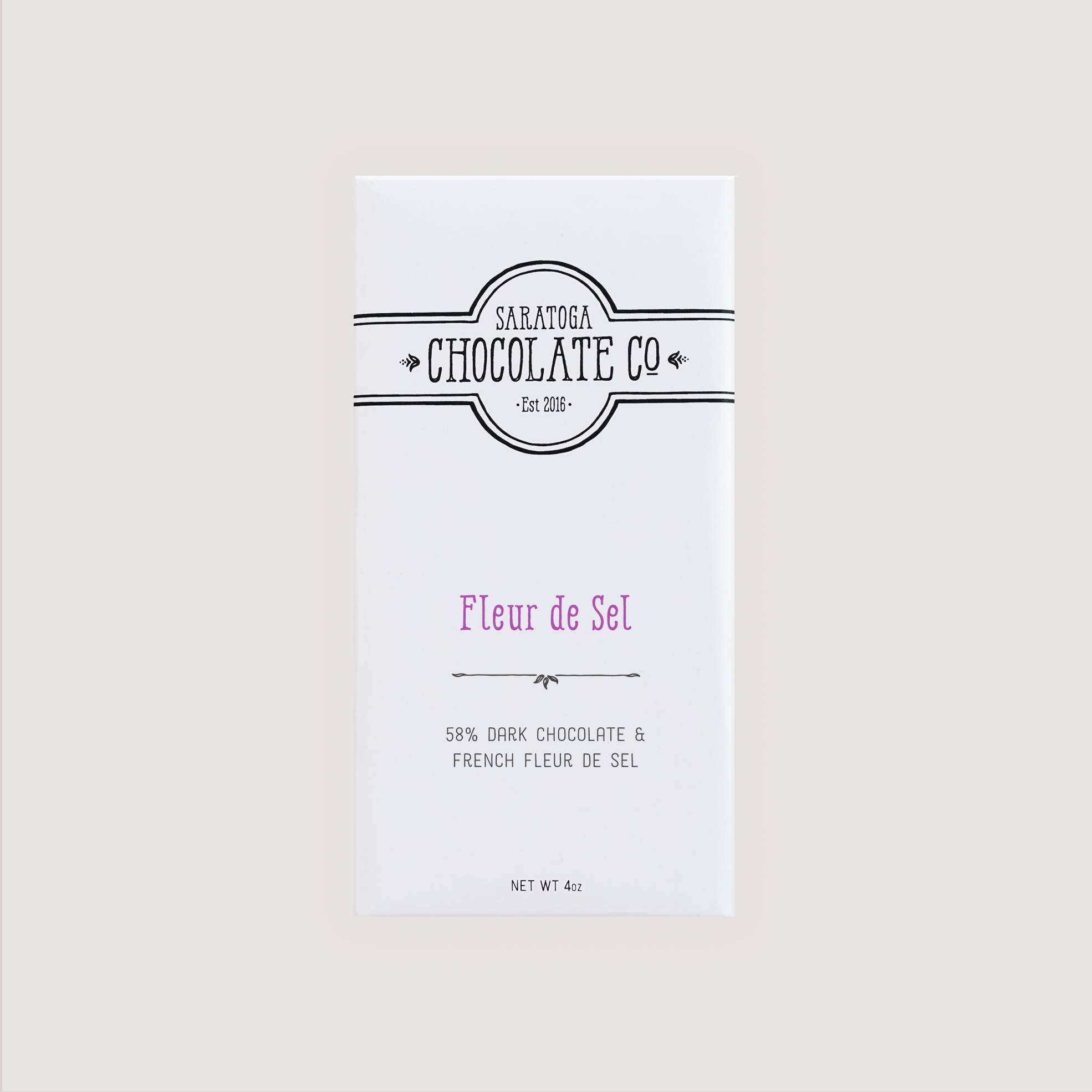 Front of Saratoga Chocolate Co. Fleur de Sel Bar wrapped in a white paper package with a purple flavor label. Label features the Saratoga Chocolate Co. logo and describes the bar as 58% dark chocolate with delicate flakes of French sea salt. This bar is vegan, gluten and dairy free.