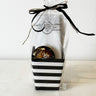 Black-and-white striped gift basket from Saratoga Chocolate Co., featuring a Latte Bar, Chocolate-Covered Espresso Beans, and Rendez Vous Bon Bons with coffee flavor, wrapped in a clear bag with a narrow black ribbon.