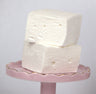 Individually wrapped Saratoga Chocolate Co. Jumbo Vanilla Marshmallow in clear cellophane packaging with an adhesive closure and label. The marshmallow appears pillow-soft, square-shaped, and dusted with a light coating of powdered sugar and cornstarch.