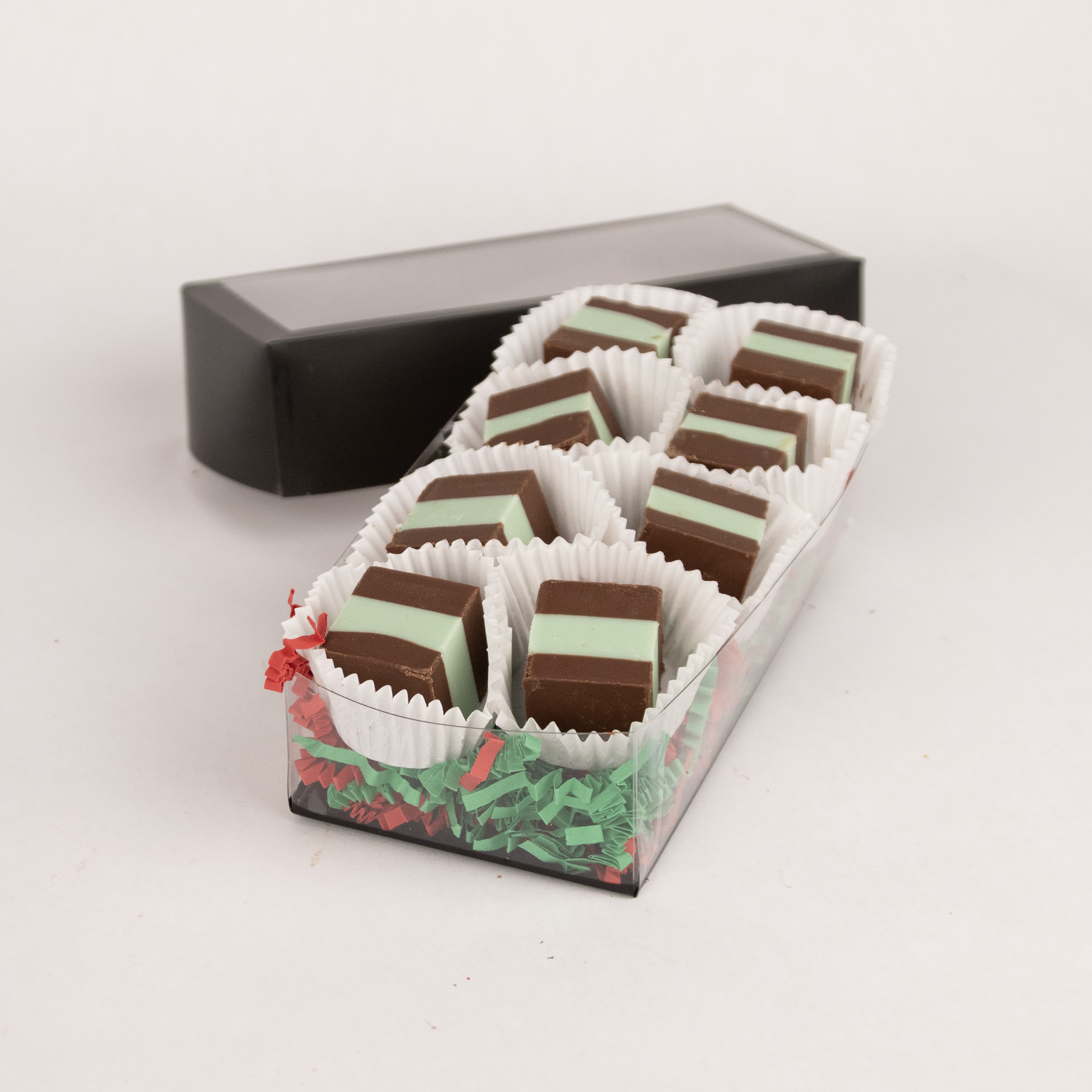 Saratoga Chocolate Co holiday box of mint meltaways, featuring smooth, square-shaped chocolates with a one square mint layer inside showing through, arranged in a black box with a clear top opening