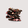 Stack of Saratoga Chocolate Co. Raspberry Almond Dark Chocolate Bark pieces, showing rich dark chocolate layered with freeze-dried raspberry pieces and toasted almond slivers. This bark is vegan, gluten and dairy free.