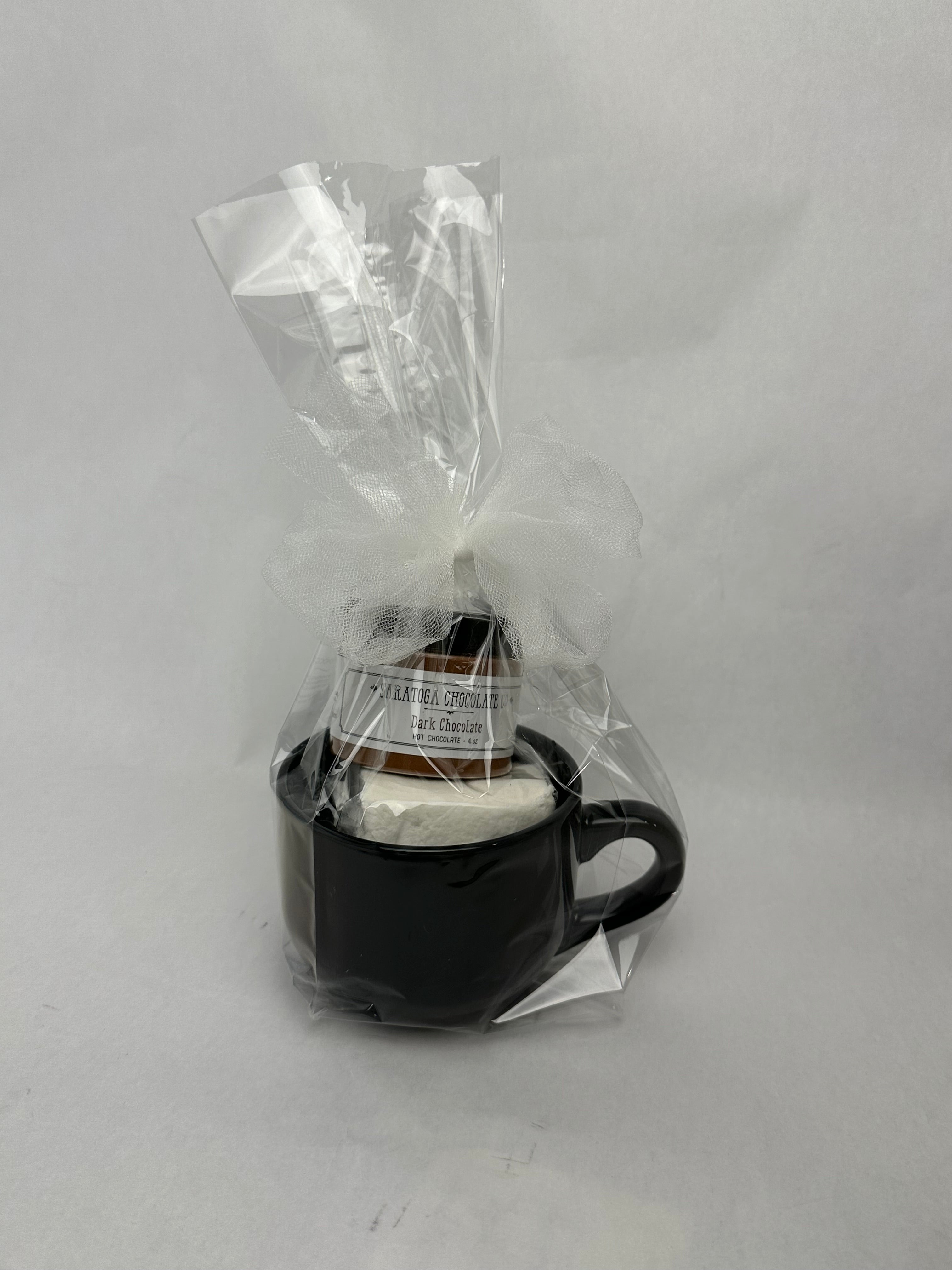 Black ceramic mug hot chocolate gift set wrapped in clear cellophane with a white bow, containing Saratoga Chocolate Co. Dark Chocolate drinking chocolate and a jumbo vanilla marshmallow.
