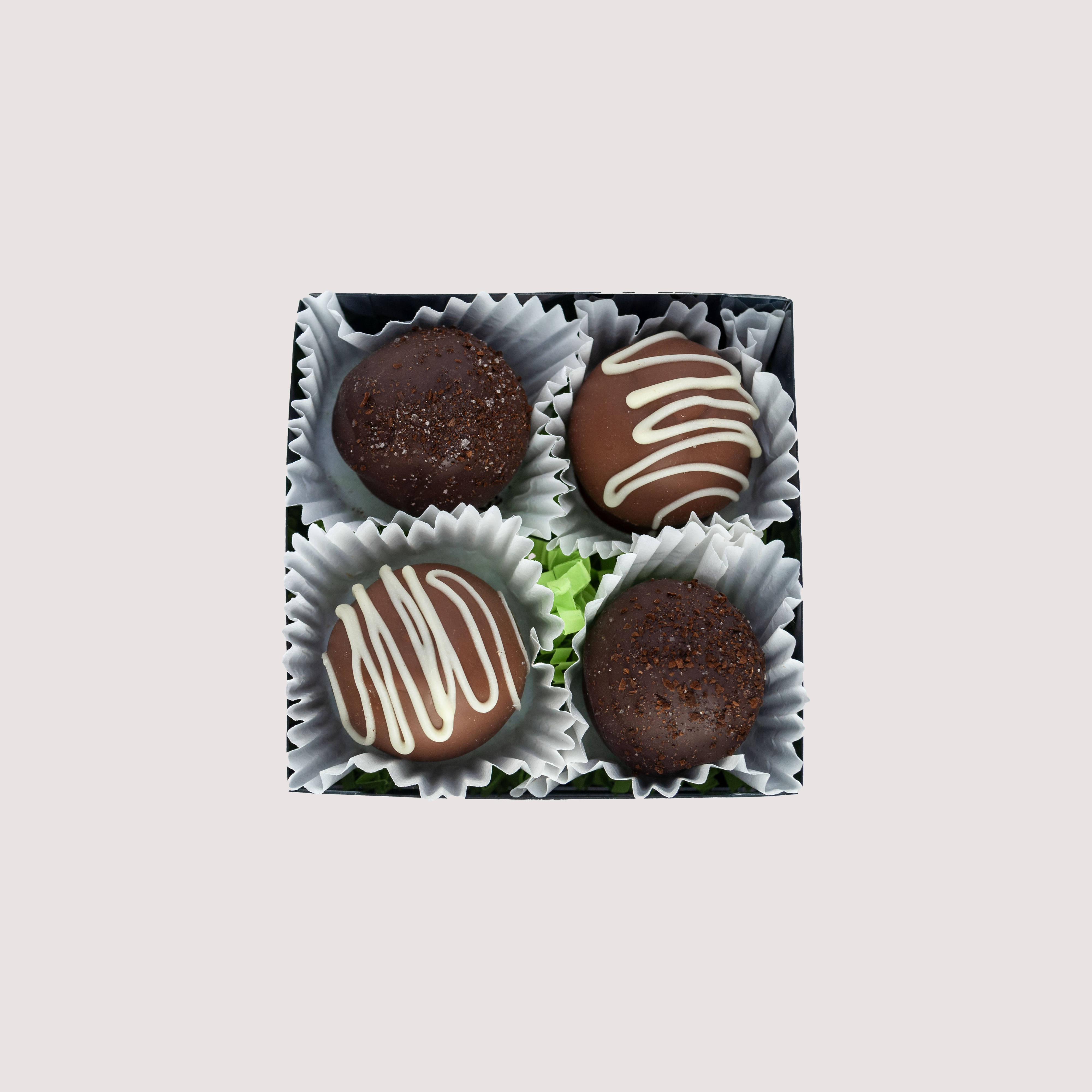 Four-piece box of Saratoga Chocolate Co. St. Patrick’s Day truffles featuring Irish Cream and Irish Coffee flavors. Includes milk chocolate Irish Cream truffles with white chocolate drizzle and dark chocolate Irish Coffee truffles topped with coffee sugar sprinkles.