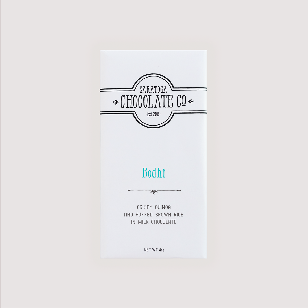 Saratoga Chocolate Co. Bodhi chocolate bar wrapped in a white paper package with a turquoise flavor label. Label features the Saratoga Chocolate Co. logo and describes the bar as crispy quinoa and puffed brown rice in milk chocolate