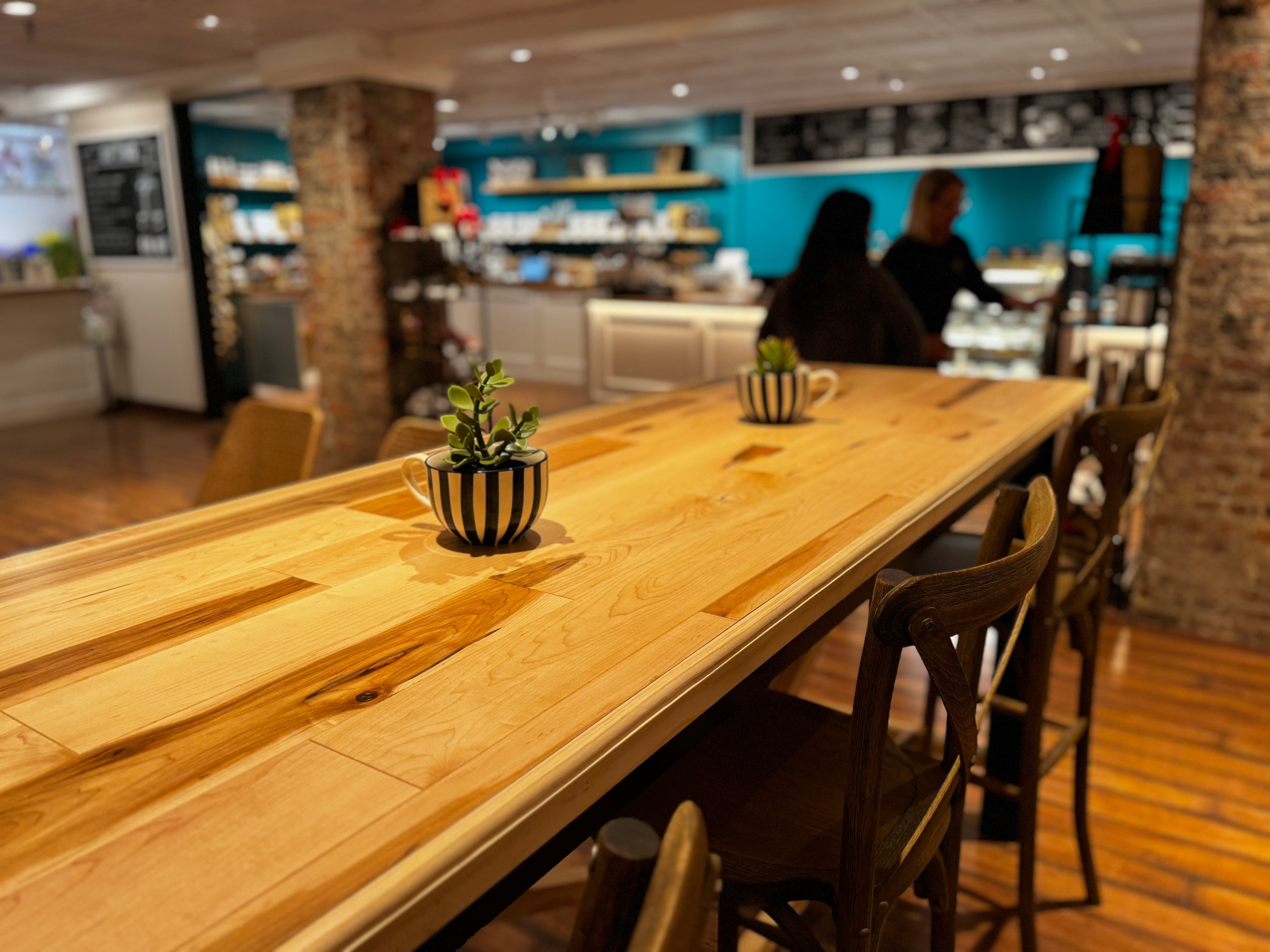 Long wooden table with chairs in a casual dining or cafe setting.