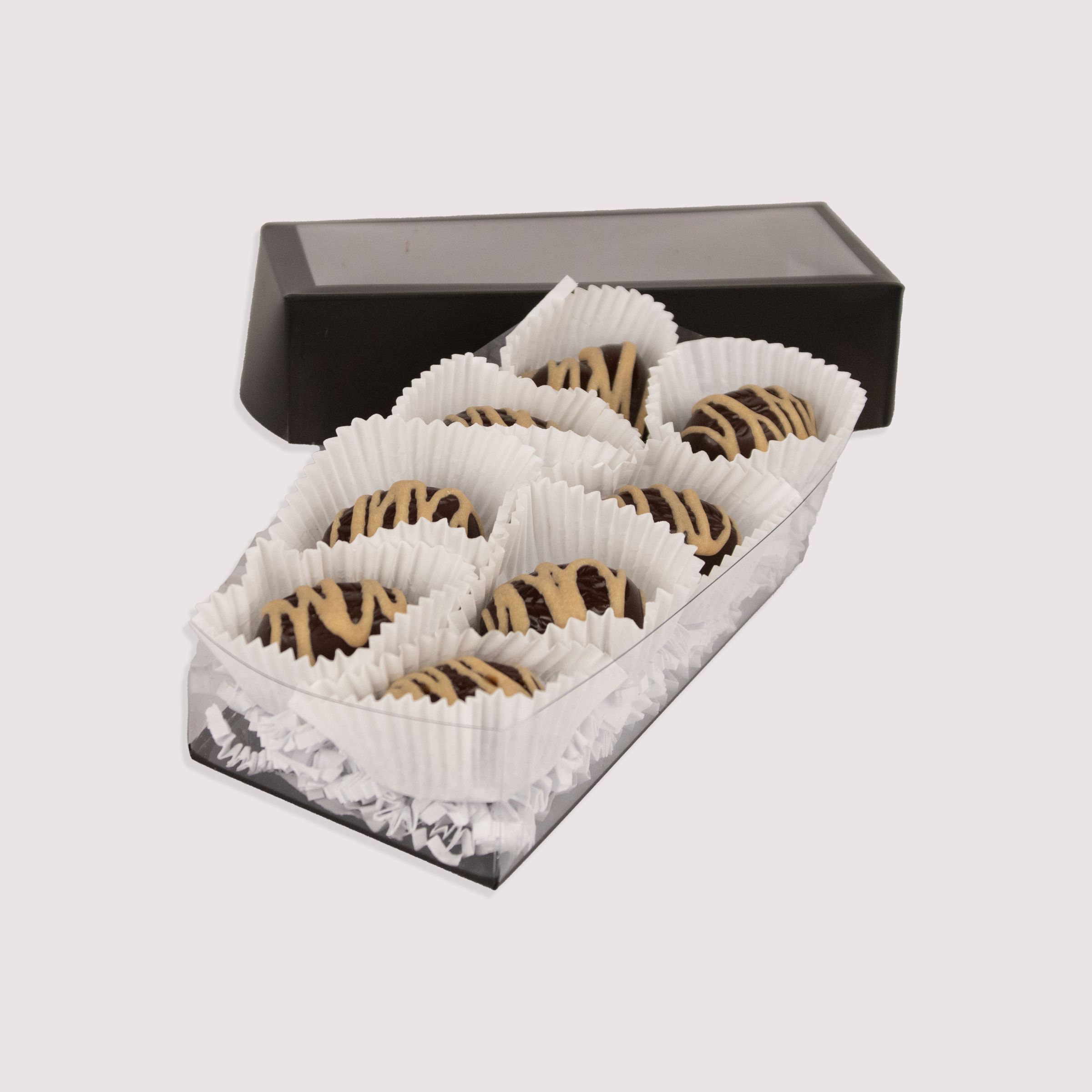 Saratoga Chocolate Co. Salted Caramel Truffle Collection featuring eight dark chocolate truffles with a salted caramel chocolate drizzle topping and a gooey amber caramel center and blended with fleur de sel. Each truffle is nestled in a white paper cup within a clear box, showcasing the artisanal presentation.
