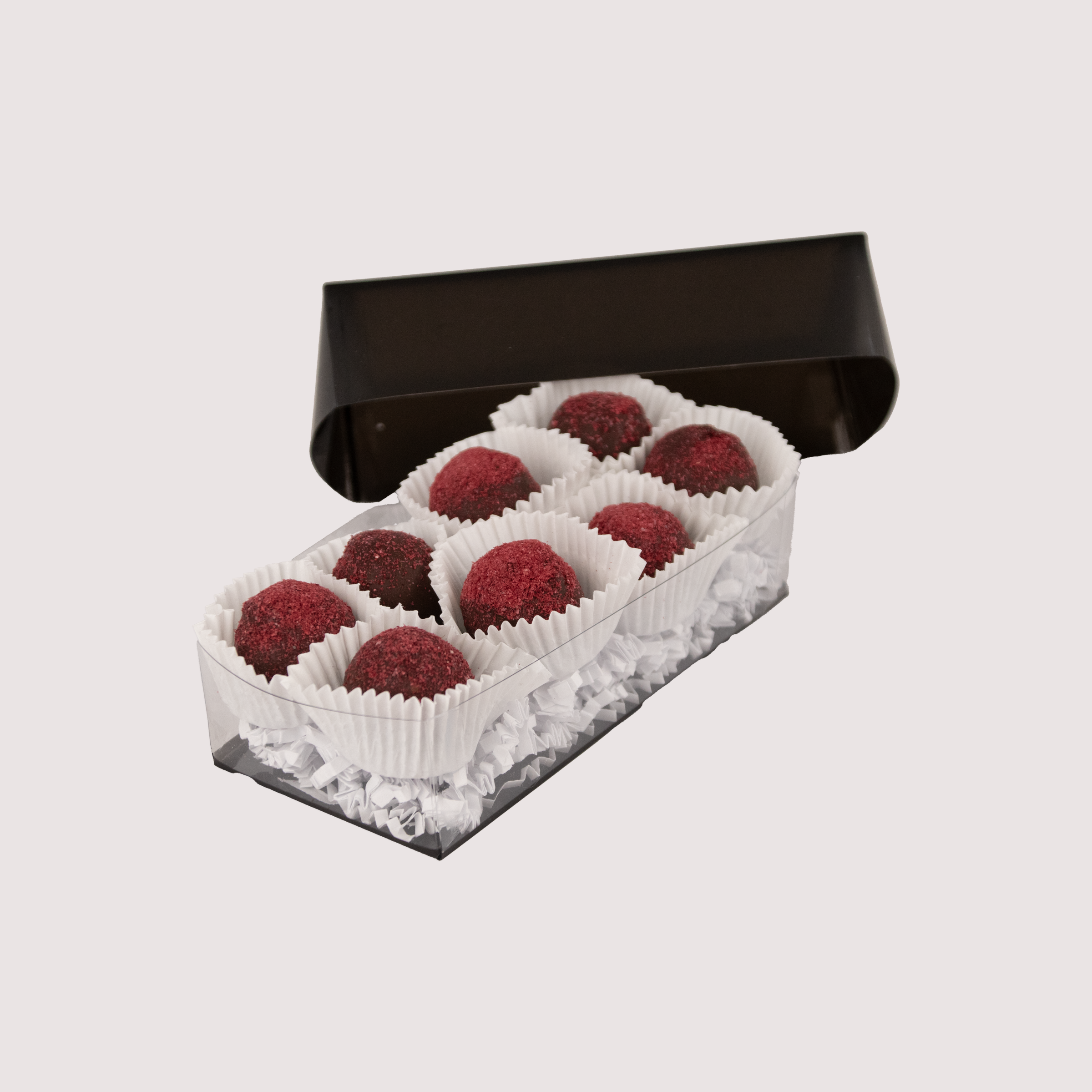 Saratoga Chocolate Co. Raspberry Truffle Collection featuring eight dark chocolate truffles nestled in white paper cups within a clear box. Each truffle has a smooth dark chocolate shell dusted with vibrant red raspberry powder.