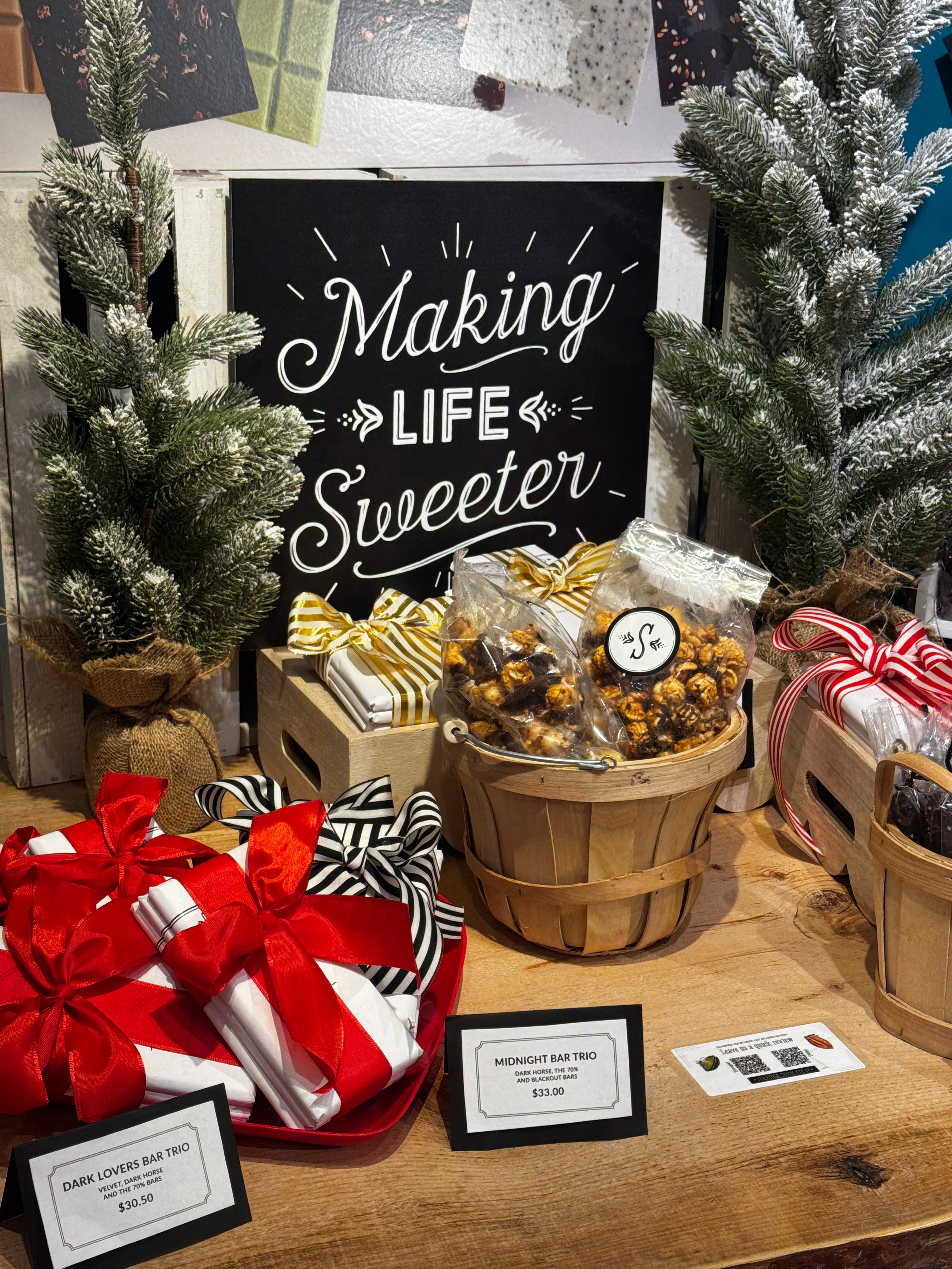 Display of chocolate bars tied with ribbons and chocolate dipped popcorn with a sign reading 'Making Life Sweeter'