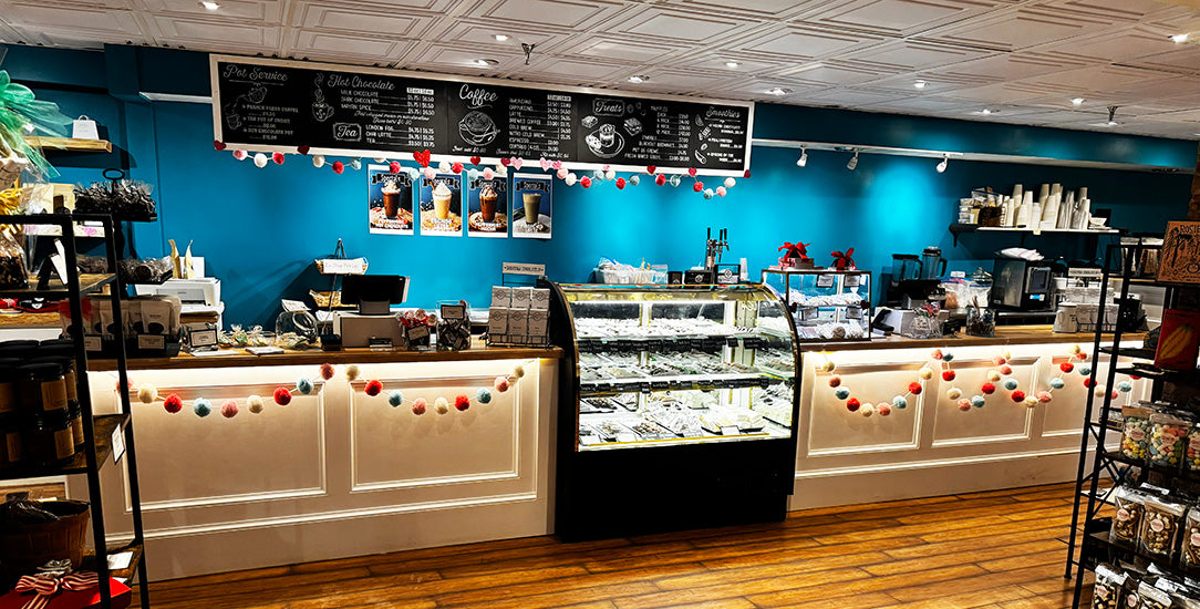 Interior of a coffee shop with blue walls, a counter, and various items on shelves.