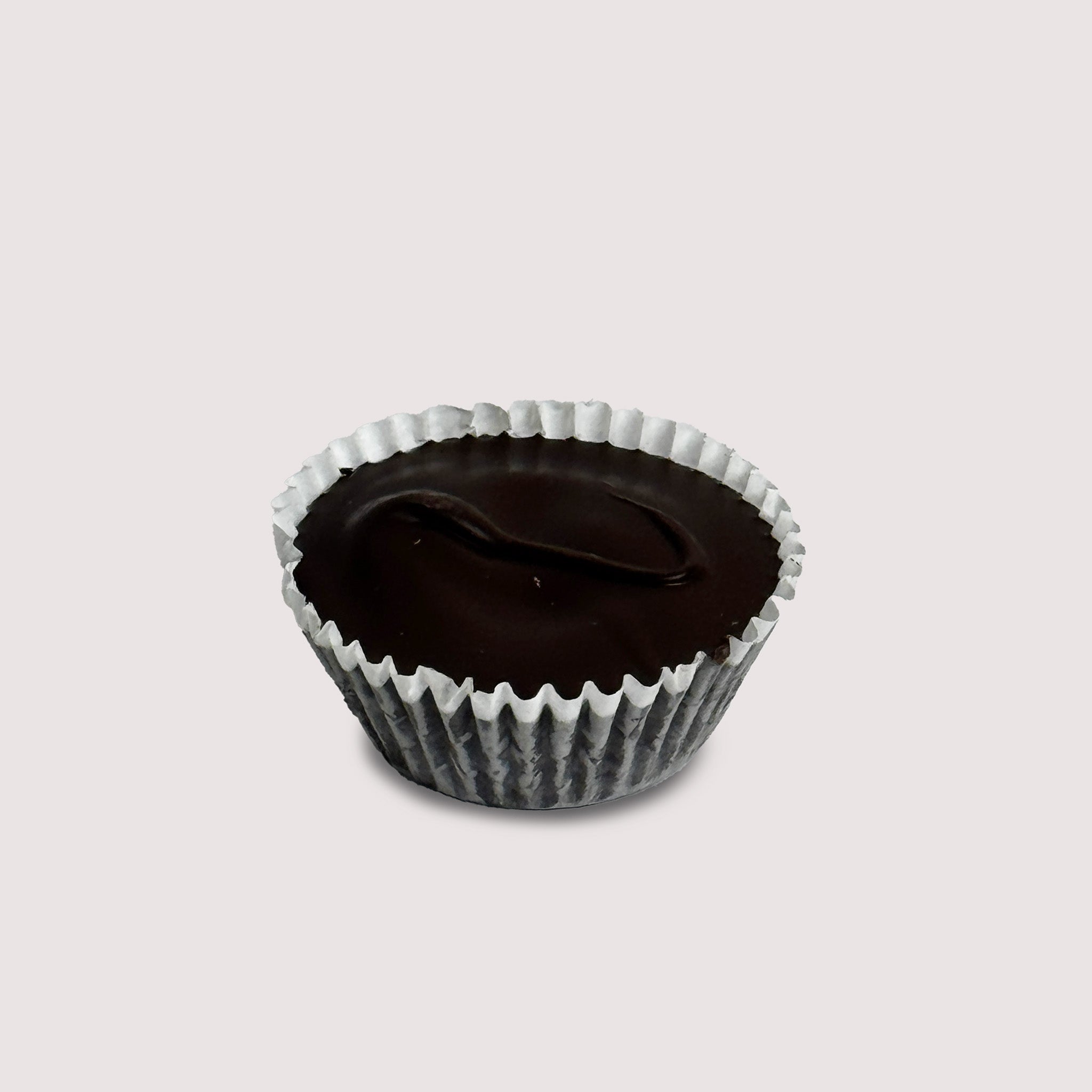 A single Dark Chocolate Peanut Butter Cup in a white paper cup, set on a light background. The dark chocolate shell is smooth and glossy, emphasizing its rich color and texture.