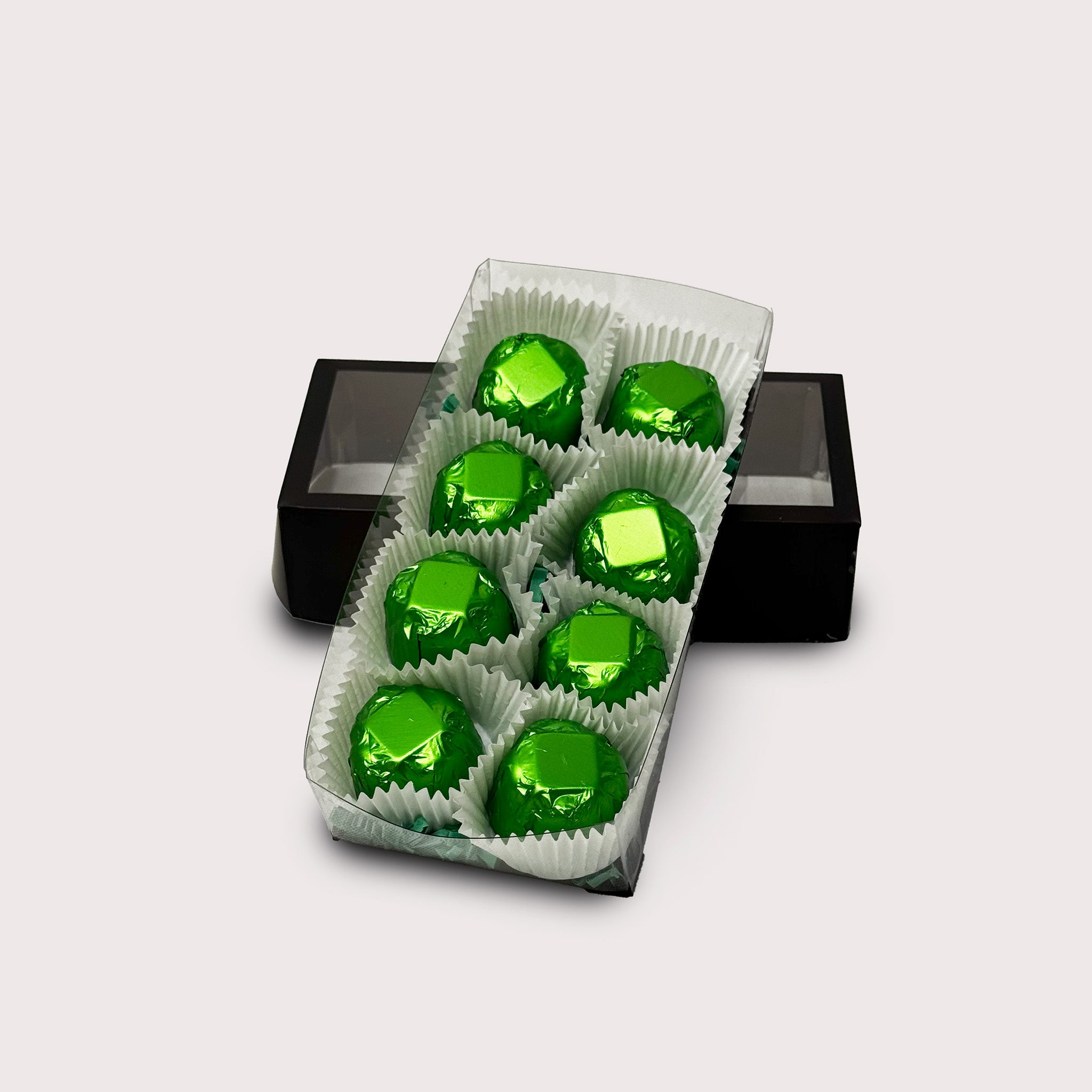 A box of 8 Dubai truffles in green foil on a neutral background