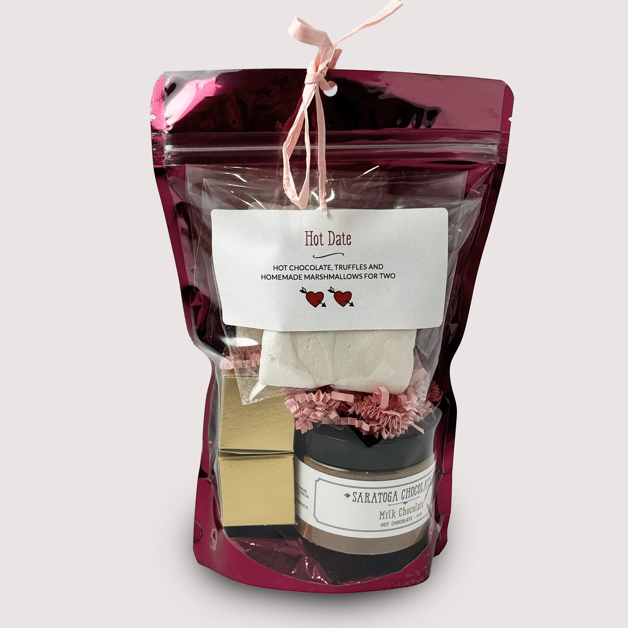 A purple gift set with a label Hot Date with hot chocolate, truffles and marshmallow by Saratoga Chocolate Co inside on a neutral background.