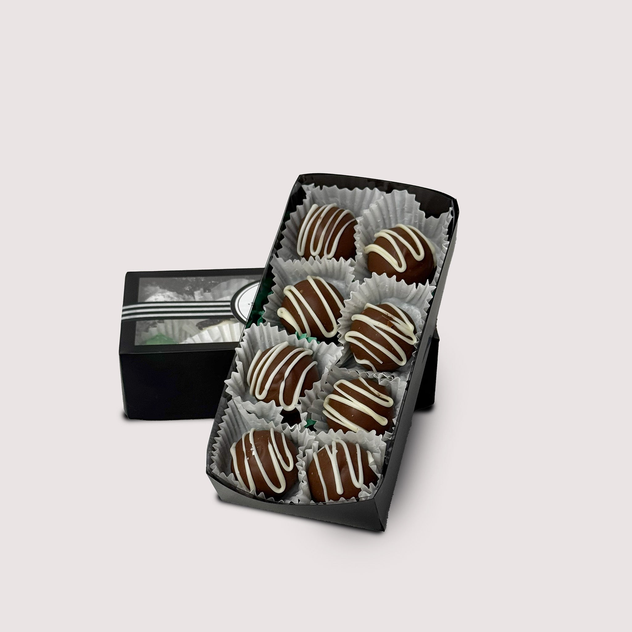 Box of dark chocolate truffles with white chocolate topping  on a light gray background