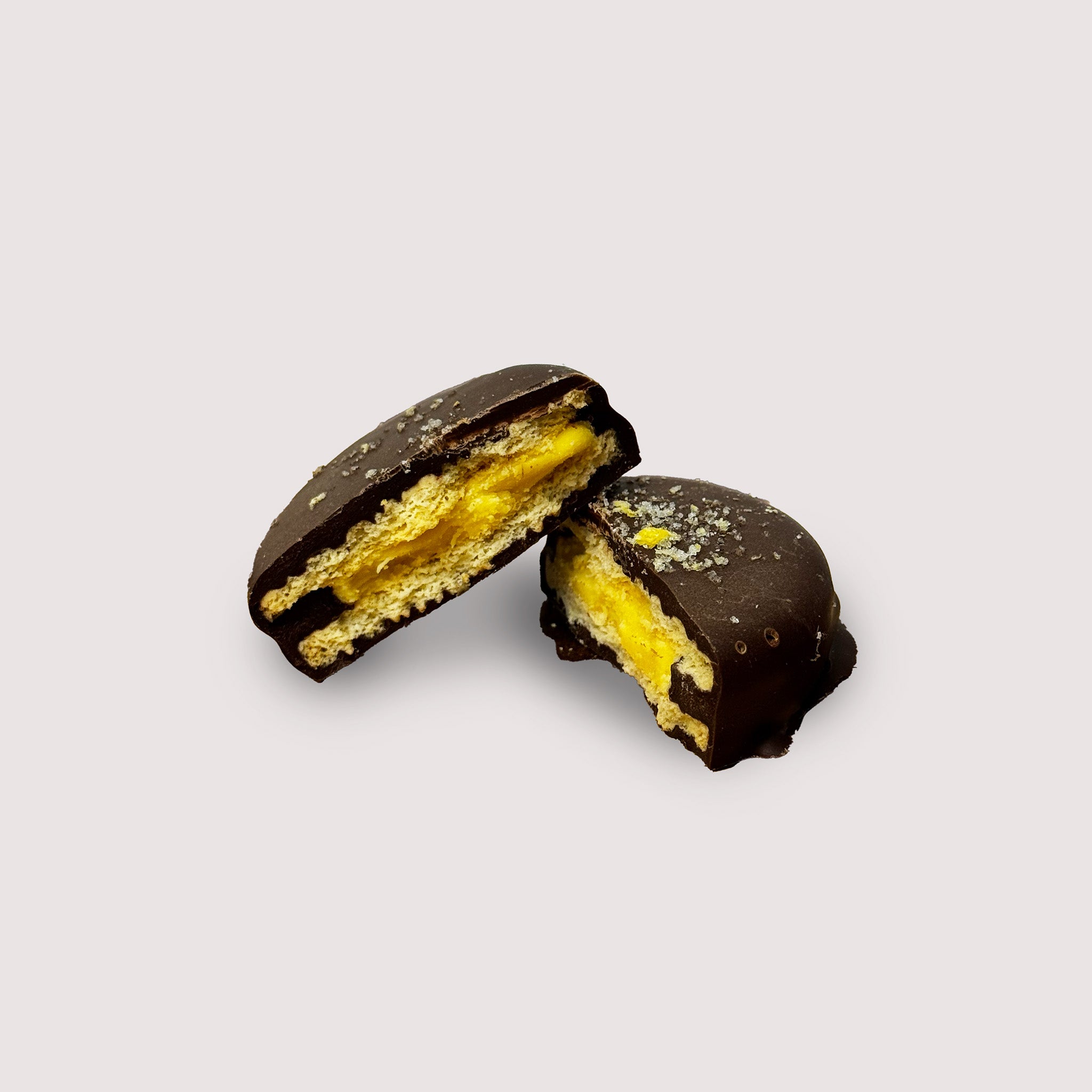 Two halves of chocolate covered lemon Oreo on a light gray background