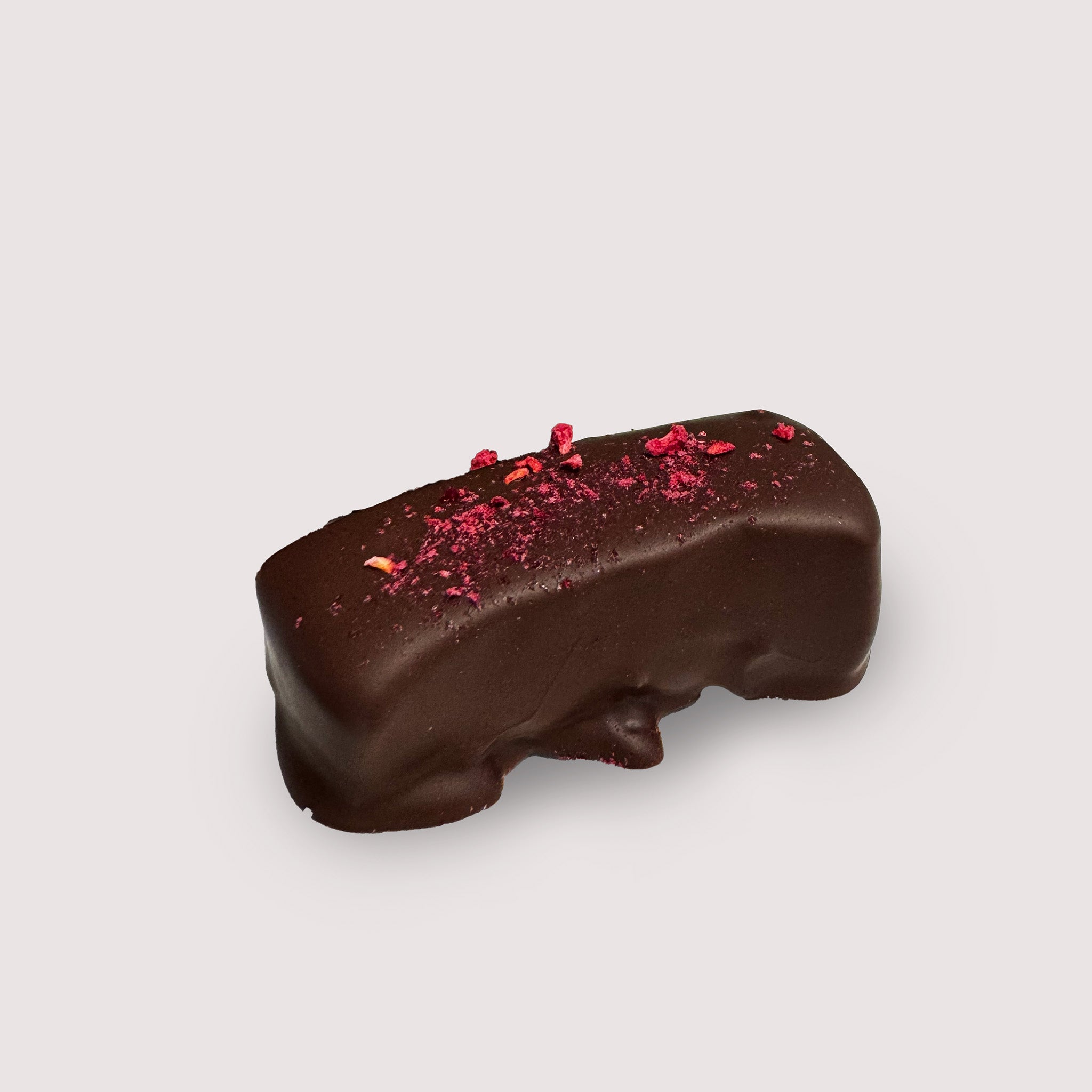 Chocolate-covered marshmallow with dried raspberries on a light gray background