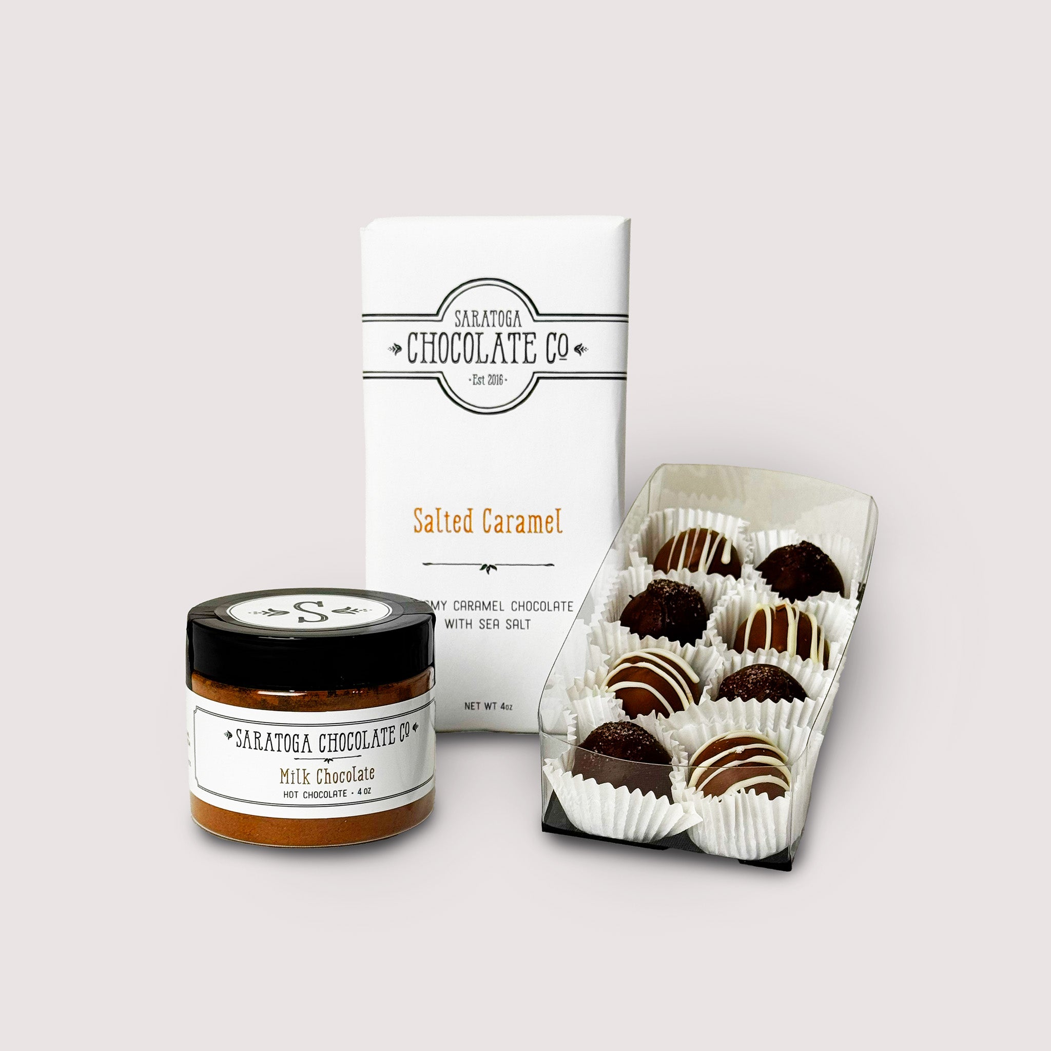 Saratoga Chocolate Co. St. Patrick’s Day gift set featuring Irish Cream and Irish Coffee truffles, a golden-wrapped Salted Caramel chocolate bar, and a tin of milk chocolate hot chocolate mix. A festive chocolate assortment perfect for celebrating St. Patrick’s Day.