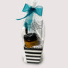 Gift basket with stripes including a chocolate bar, candle, and chocolate bark on a white background