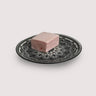 One piece of a jumbo raspberry marshmallow on a plate with black and white pattern.