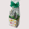 Gift bag with floral design, a Chocolate bar, powdered toffee almonds, and chocolate dipped Oreo in a clear bag on a light gray background