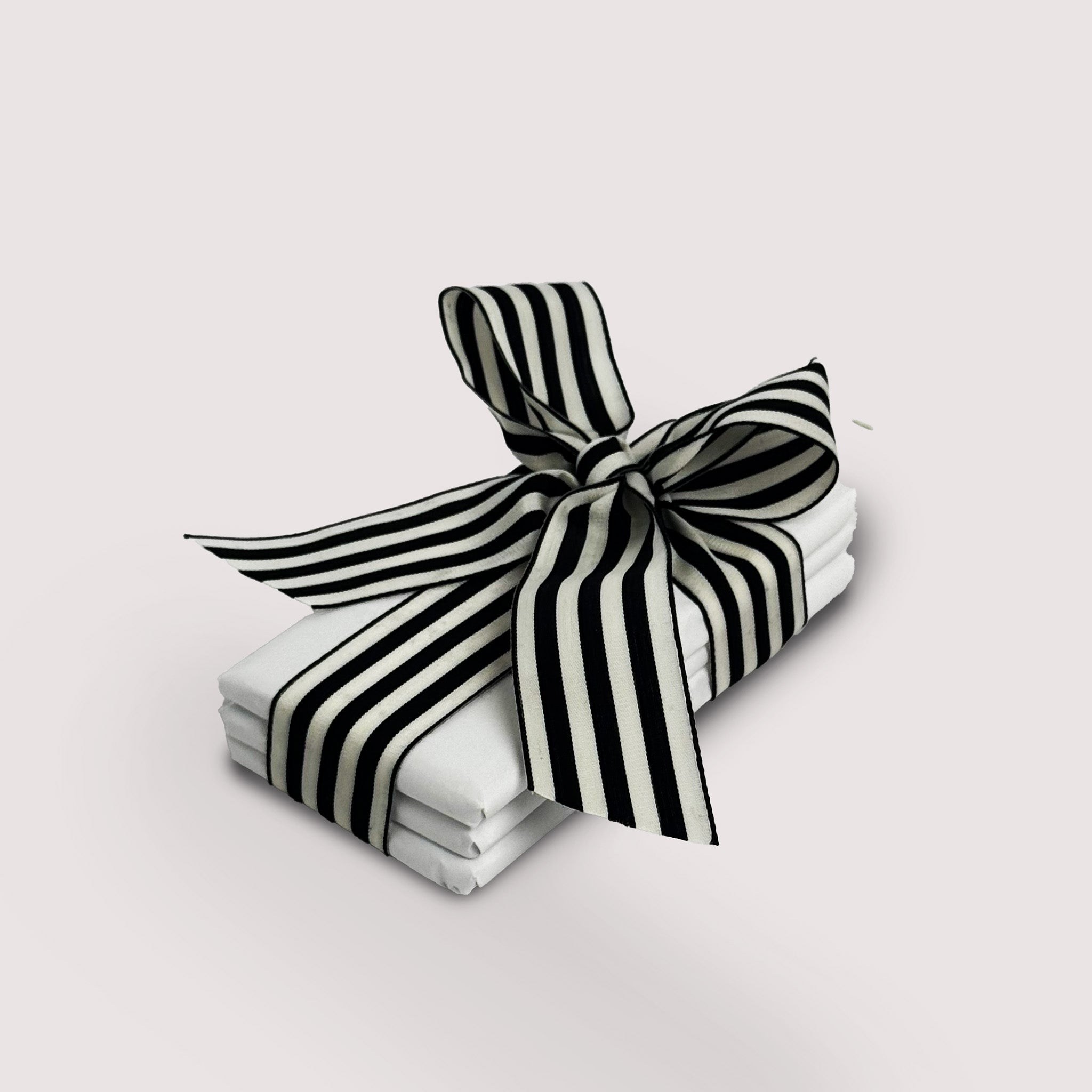 Stack of chocolate bars by Saratoga Chocolate Co with a black and white striped bow on a light gray backgrounds 