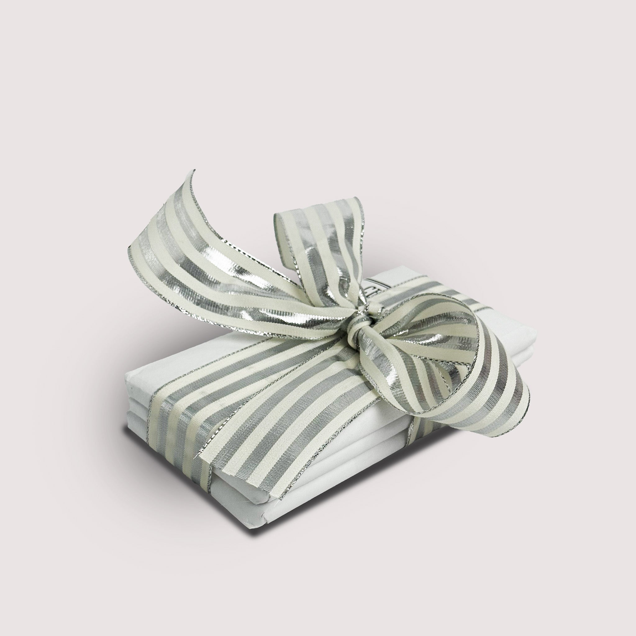Stack of chocolate bars by Saratoga Chocolate Co with a silver and white striped bow on a light gray backgrounds 
