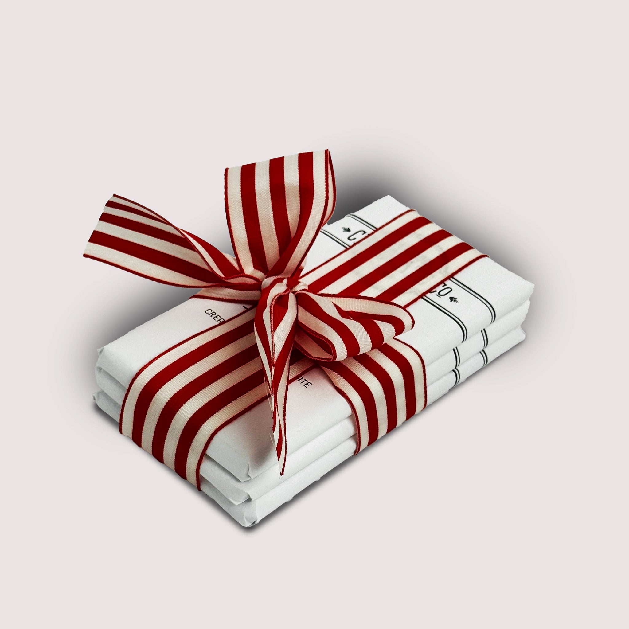 Stack of chocolate bars by Saratoga Chocolate Co with a red and white striped bow on a light gray backgrounds 