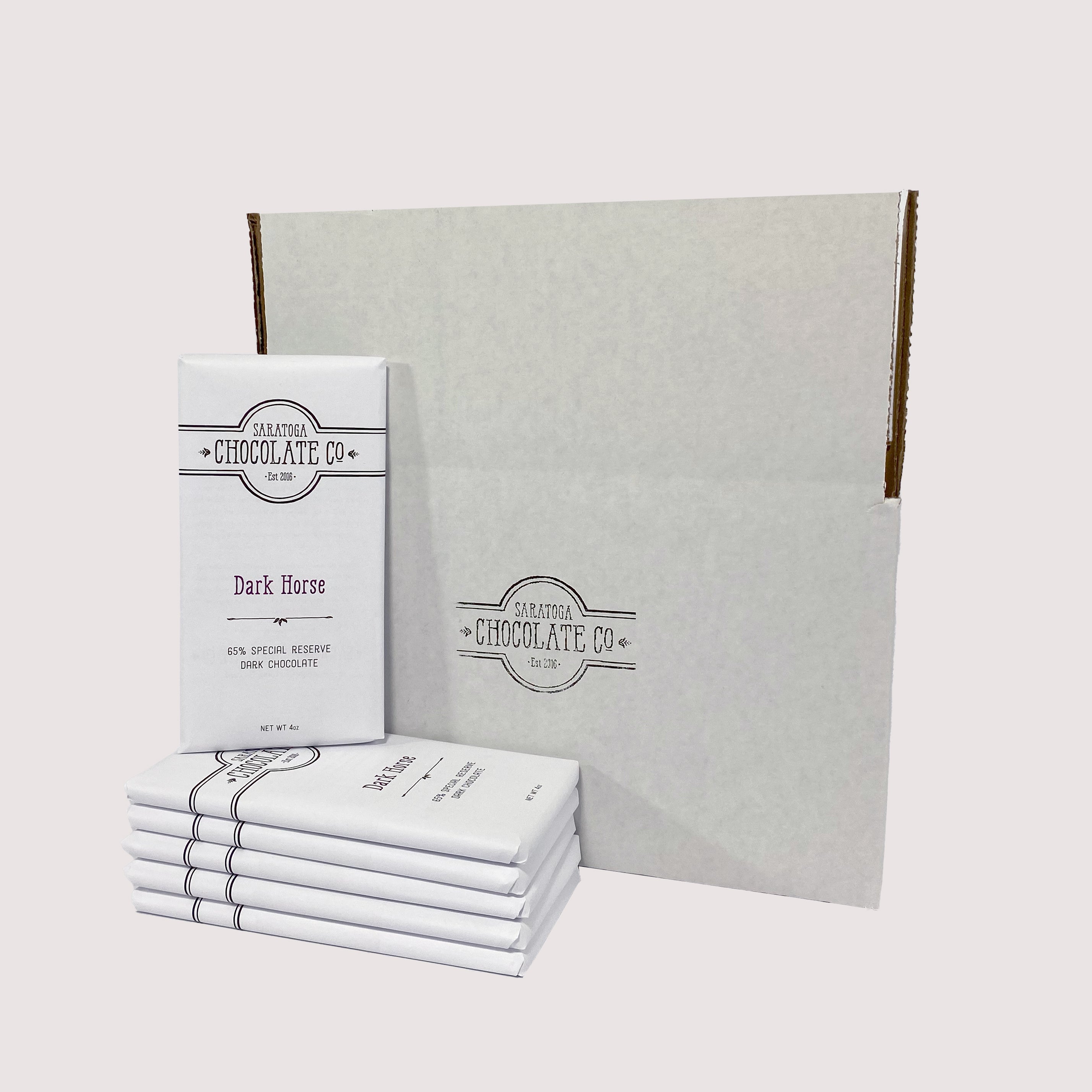 Stack of Saratoga Chocolate Co. bars arranged in front of a white box, with a Dark Horse Chocolate bar facing forward and prominently displayed.