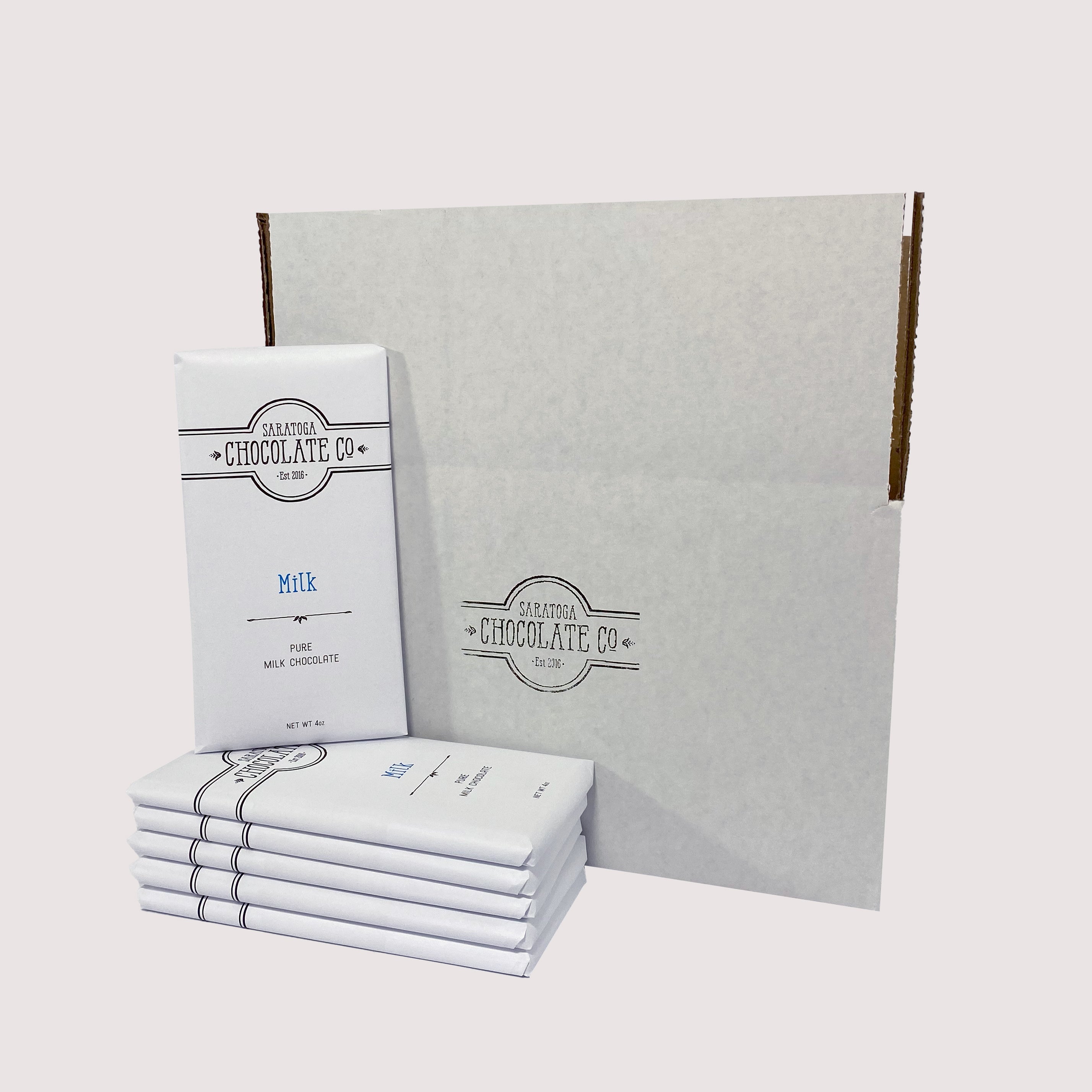 Stack of Saratoga Chocolate Co. bars arranged in front of a white box, with a Milk Chocolate bar facing forward and prominently displayed.