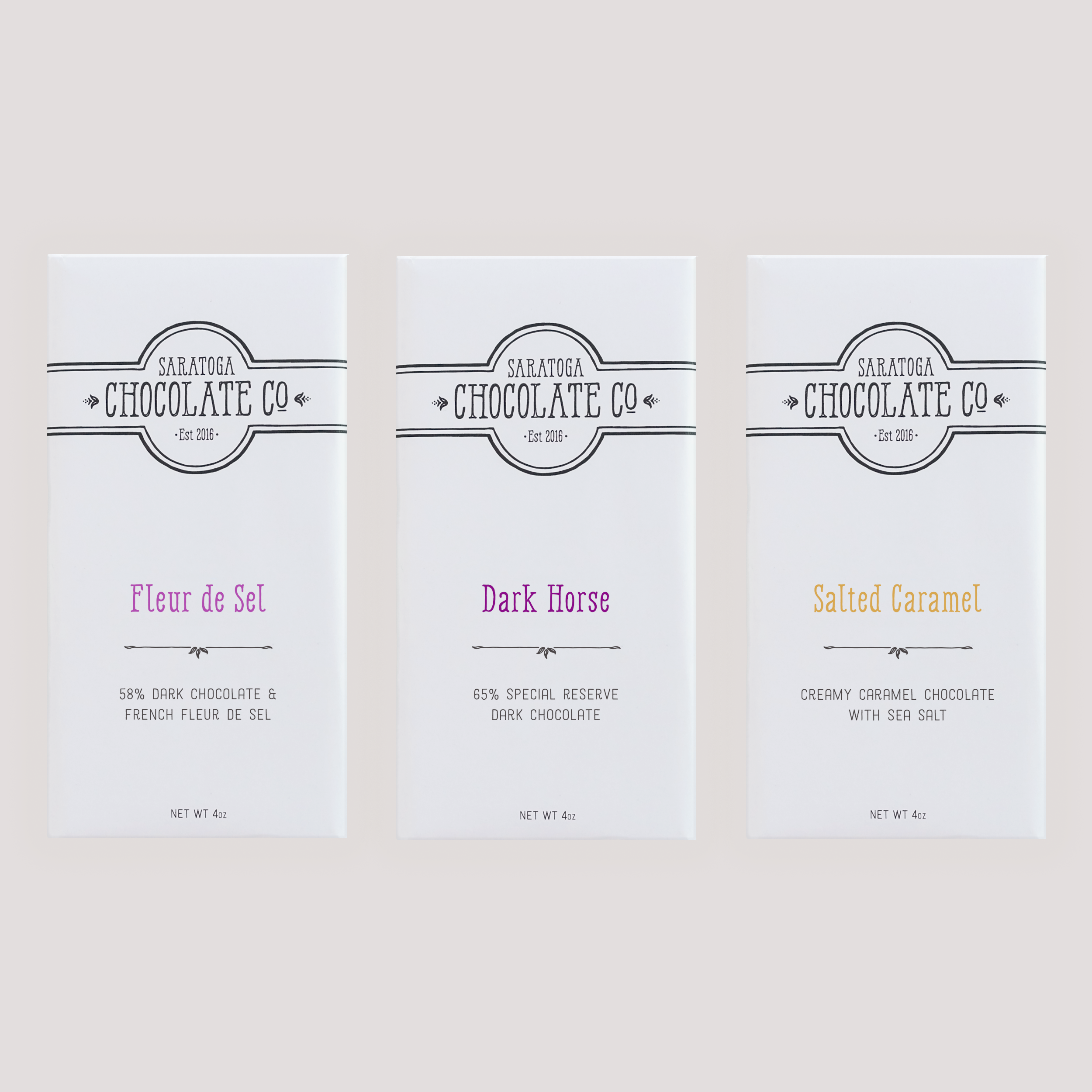 Salt Lovers Trio by Saratoga Chocolate Co. featuring three chocolate bars: Fleur de Sel, Dark Horse and Salted Caramel with sea salt, wrapped in white packaging with logo, arranged side by side.