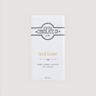 Saratoga Chocolate Co. Salted Caramel chocolate bar wrapped in a white paper package with a copper flavor label. Label features the Saratoga Chocolate Co. logo and describes the bar as creamy caramel chocolate with a touch of sea salt. This bar is gluten free.