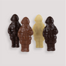 Four unwrapped solid chocolate Santas made with four different types of chocolate, standing upright in a white fluted bowl, crafted by Saratoga Chocolate Co.