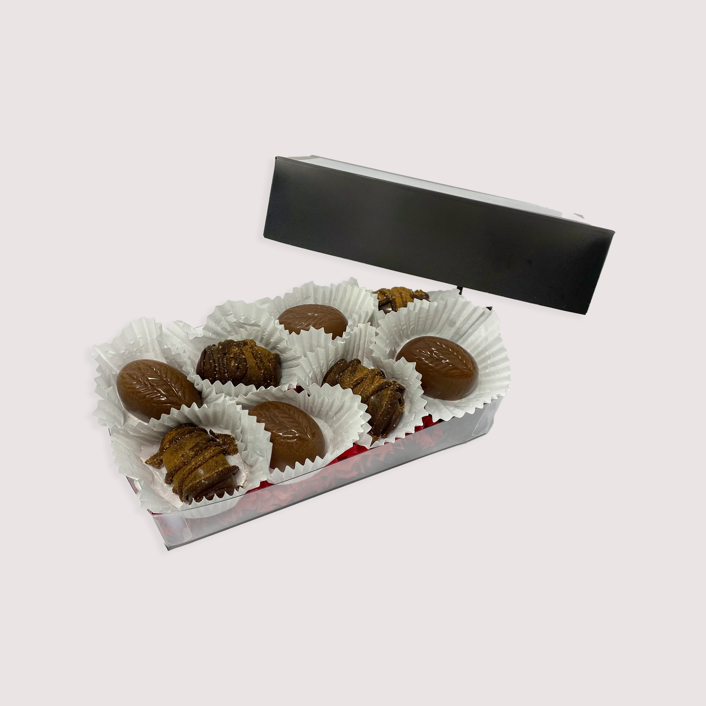 Box of fall-themed assorted truffles by Saratoga Chocolate Co, featuring eight handcrafted chocolates in seasonal colors and designs, arranged in a black box with a clear lid.