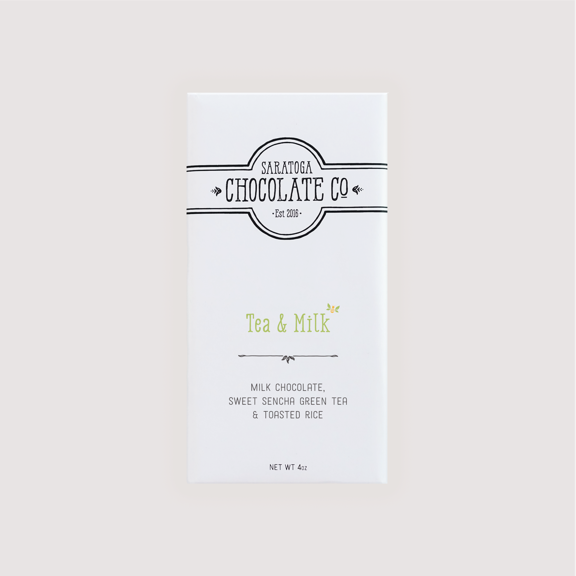Front of Saratoga Chocolate Co. Tea & Milk  Bar wrapped in a white paper package with a moss green flavor label. Label features the Saratoga Chocolate Co. logo and describes the bar as milk chocolate sweet Sencha green tea and toasted rice. This bar is gluten free.

