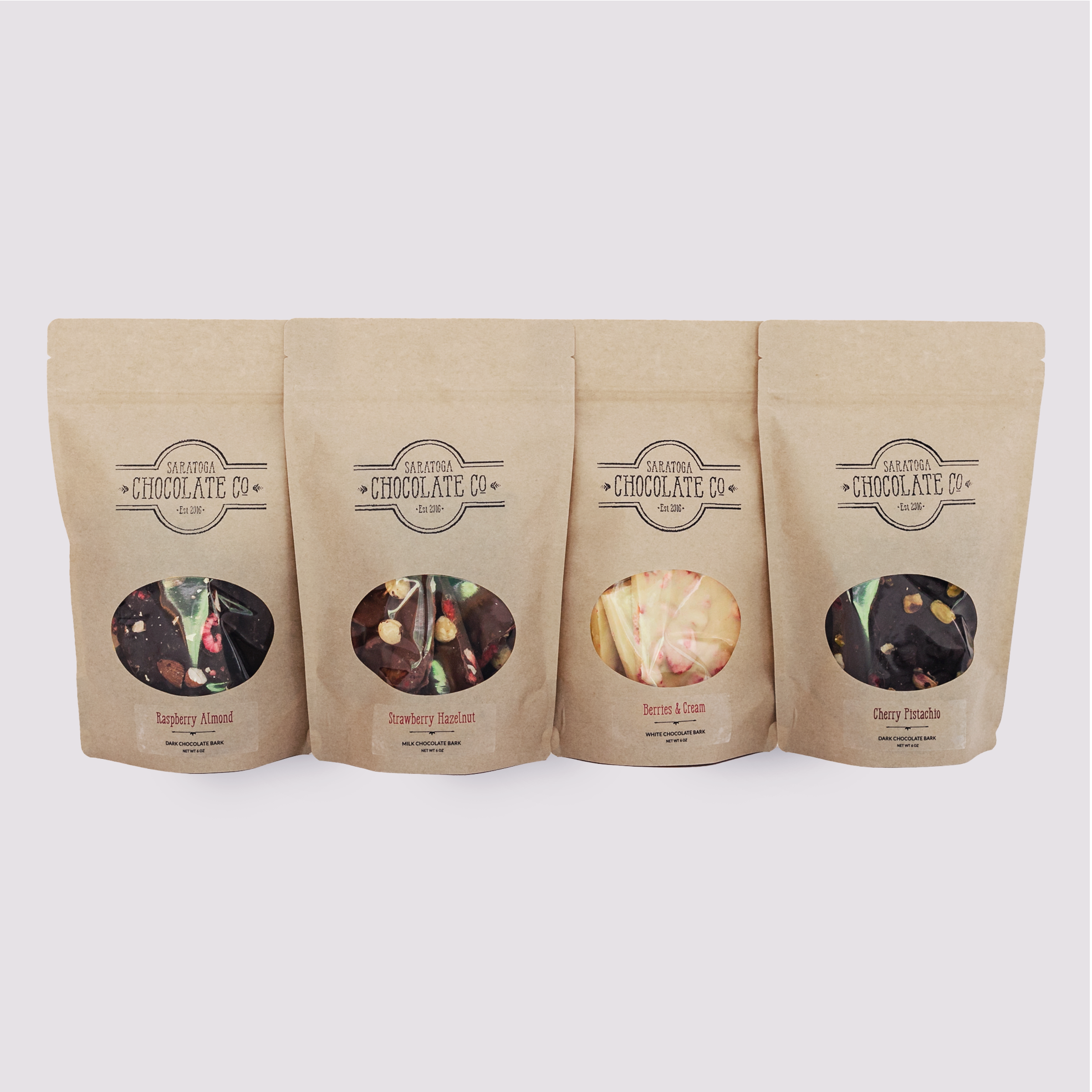 Four bags of Saratoga Chocolate Bark from left to right: Raspberry Almon, Strawberry Hazelnut, Berries & Cream, Cherry Pistachio.