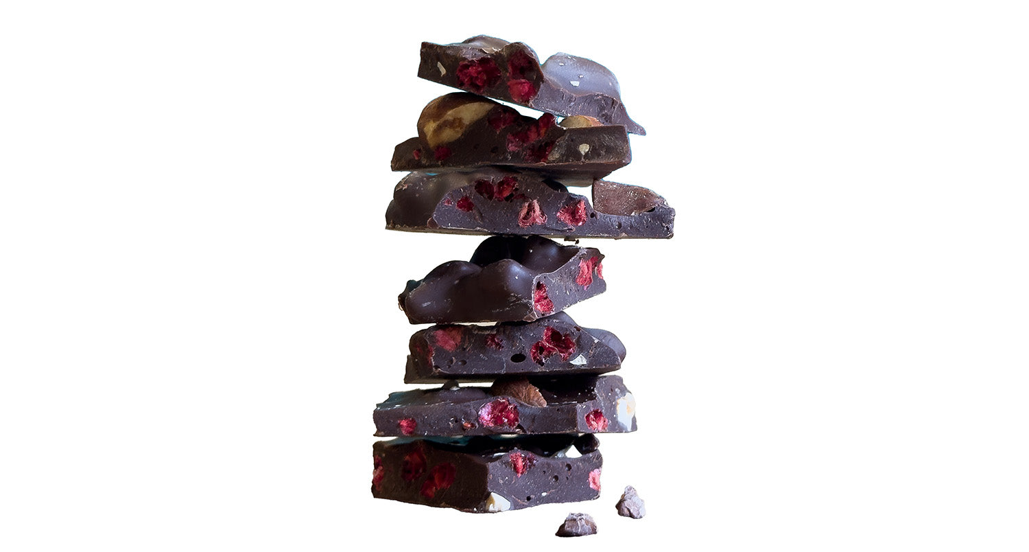 Stack of dark chocolate barks with berries and almonds on a white background