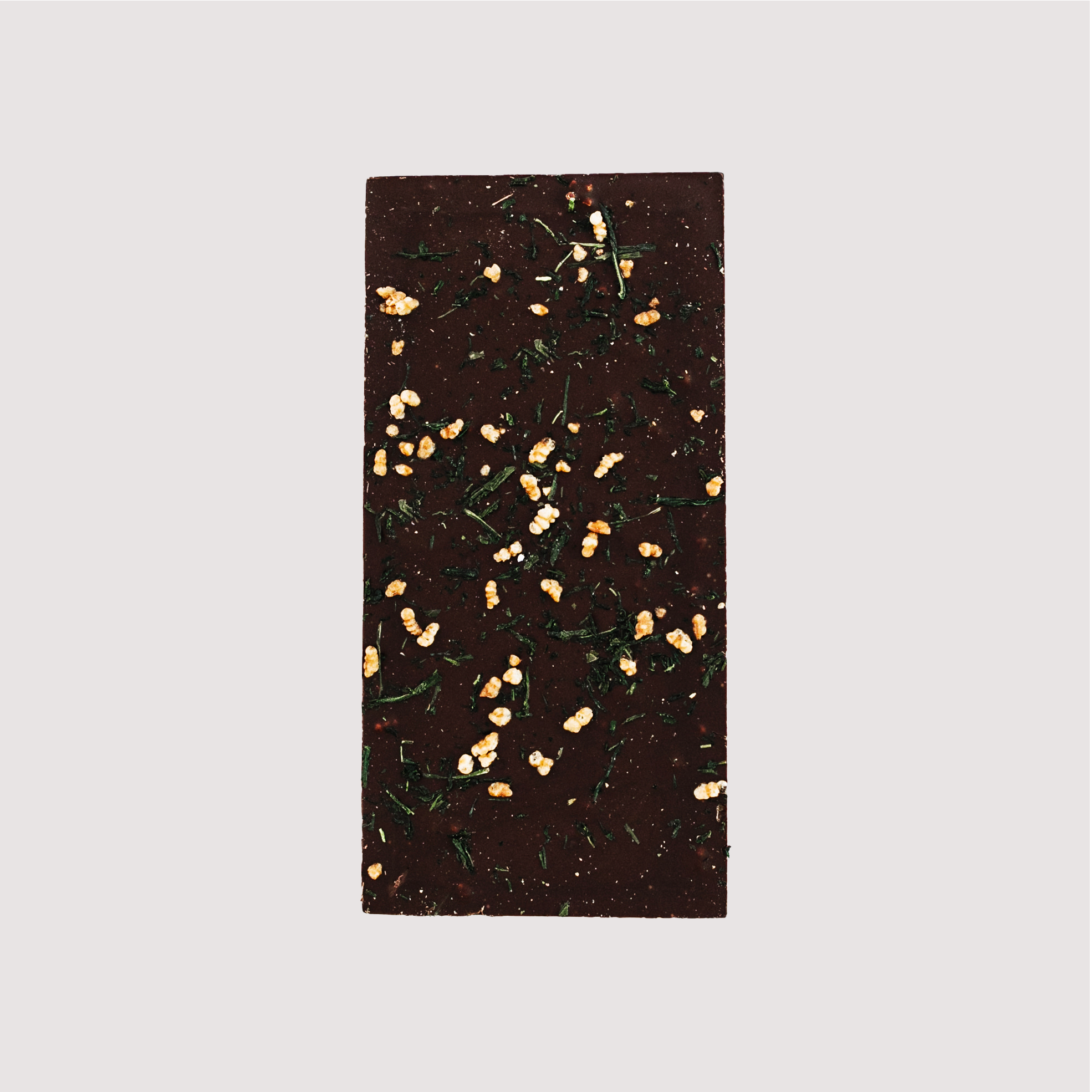 Unwrapped Saratoga Chocolate Co. Genmai Cha Bar, back side revealing textured dark chocolate with visible toasted rice pieces and tea leaf flakes from the infused roasted green tea blend. This bar is vegan, gluten and dairy free.