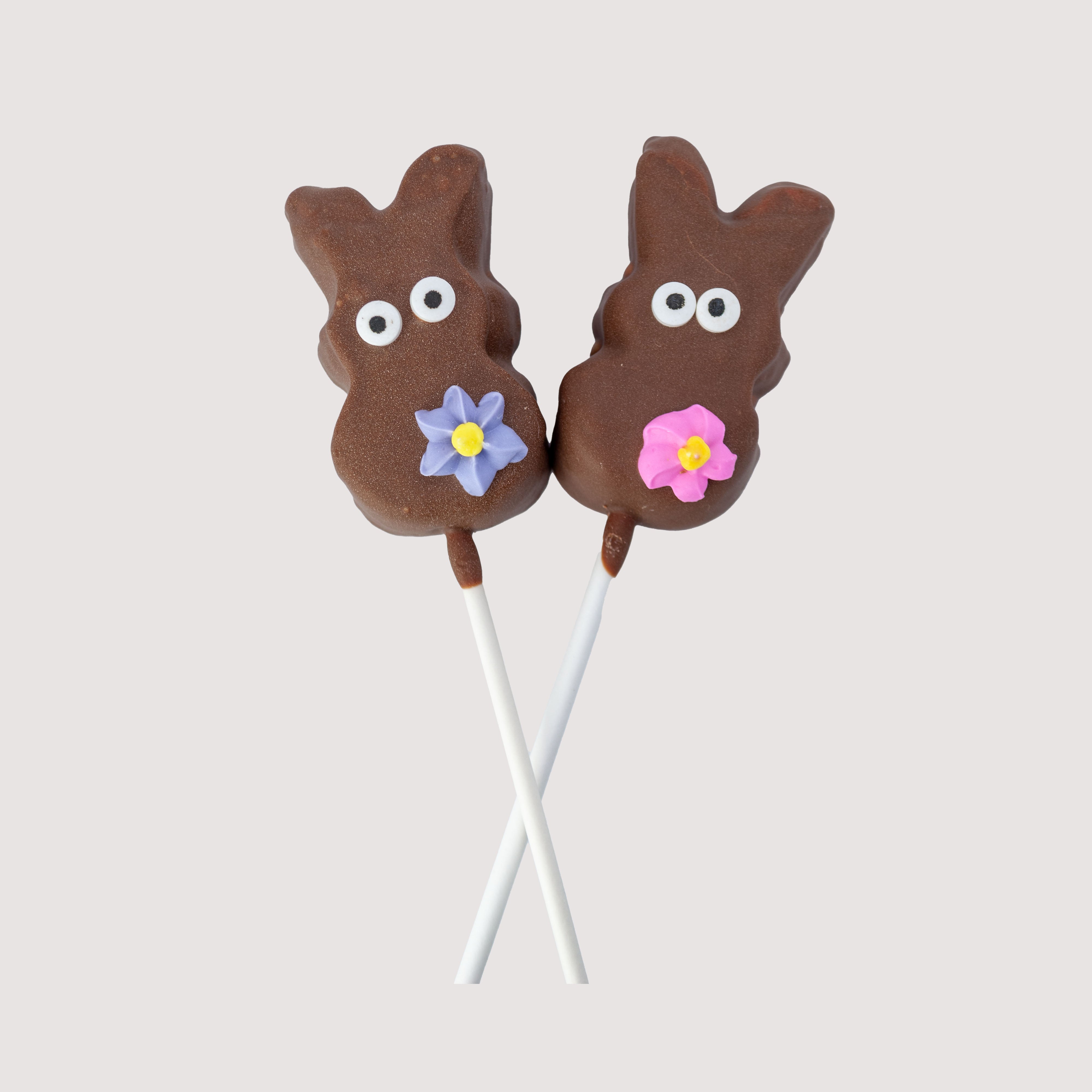 Two festive chocolate pops shaped like a bunny. Each marshmallow Peep - dipped in creamy milk chocolate and topped with a sweet, handmade spring flower. Created by Saratoga Chocolate Co.